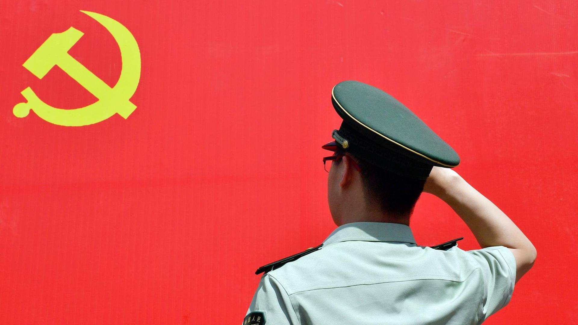 Ein Polizist salutiert vor der roten Flagge der Kommunistischen Partei Chinas. Ein Polizist salutiert vor der roten Flagge der Kommunistischen Partei Chinas.