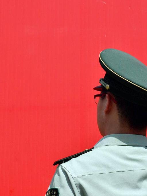 Ein Polizist salutiert vor der roten Flagge der Kommunistischen Partei Chinas.
