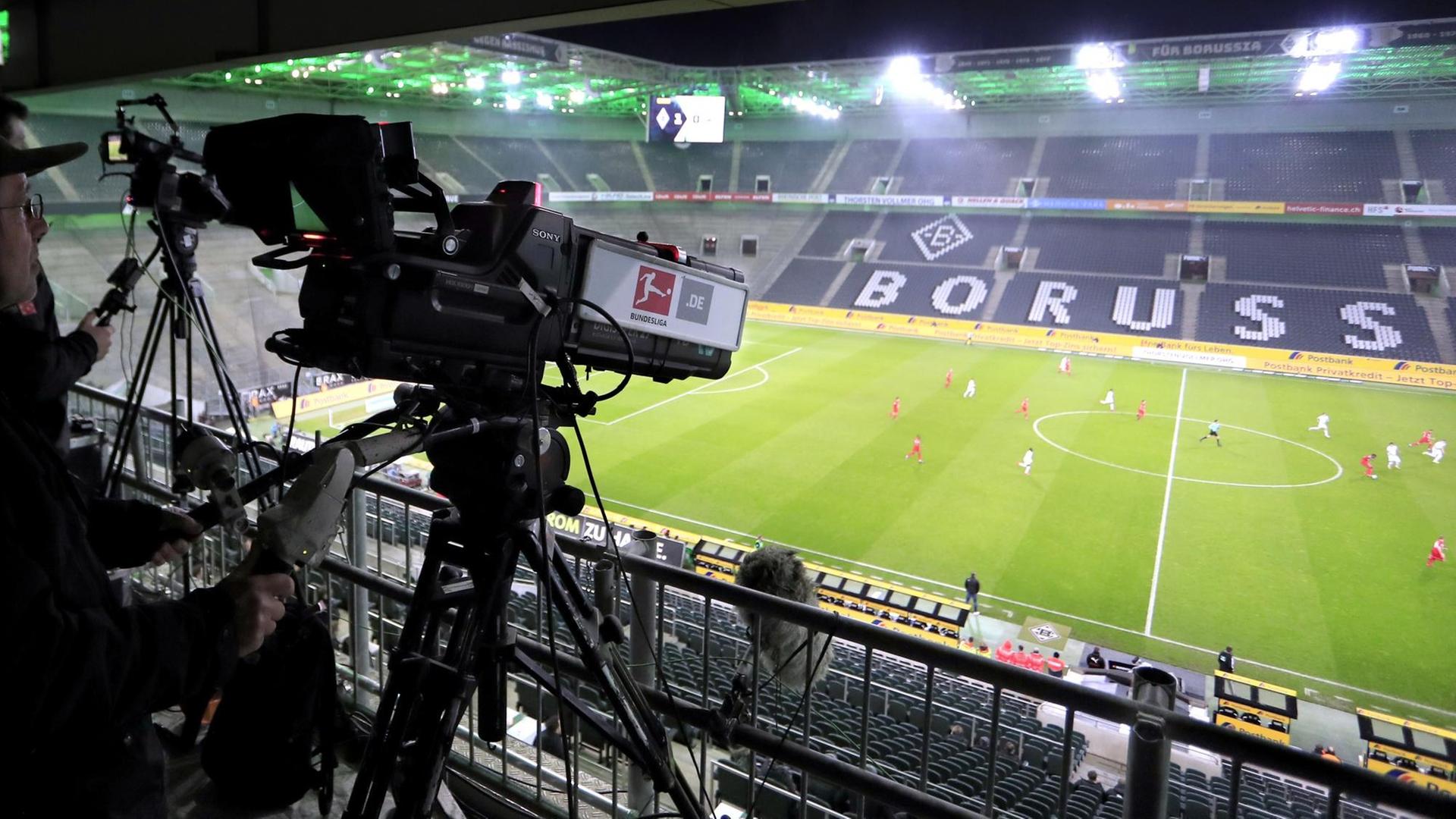 Eine Kamera filmt ein Fußball-Spiel in einem Stadion ohne Zuschauer. Eine Kamera filmt ein Fußball-Spiel in einem Stadion ohne Zuschauer.