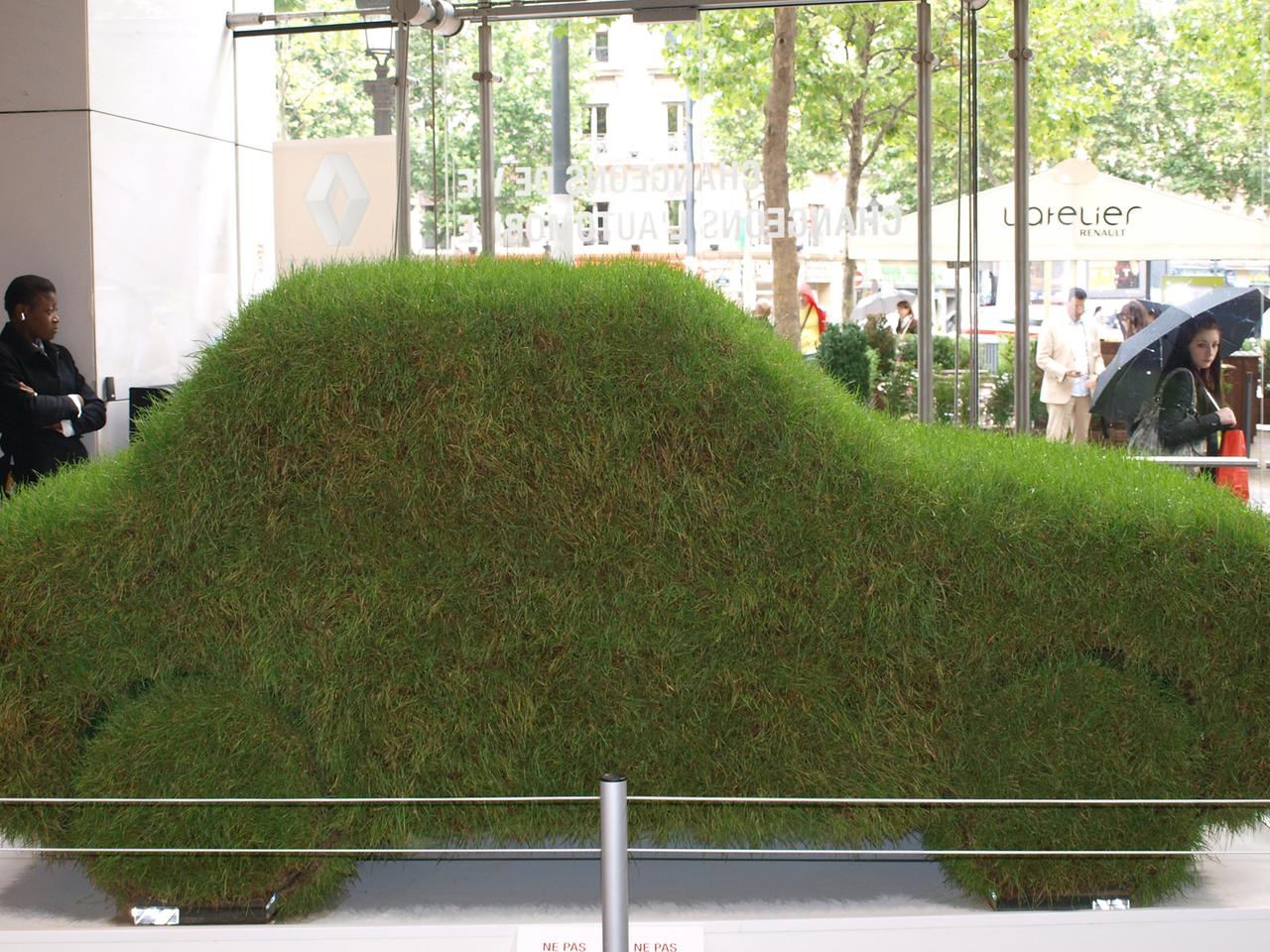 In einem Autosalon ist ein mit Gras bedecktes Auto zu sehen.
