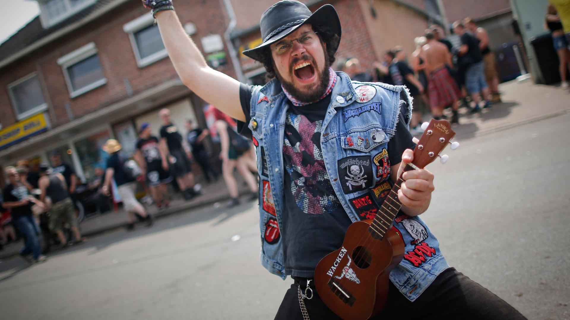 Ein Metal-Fan posiert mit seiner Ukulele beim 24. Heavy Metal Wacken Open Air Festival (WOA) 2013 in Wacken. Ein Metal-Fan posiert mit seiner Ukulele beim 24. Heavy Metal Wacken Open Air Festival (WOA) 2013 in Wacken.