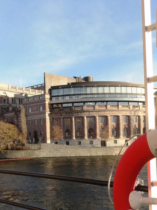 Man sieht den schwedischen Reichstag in Stockholm, vorne rechts ein Rettungsring.