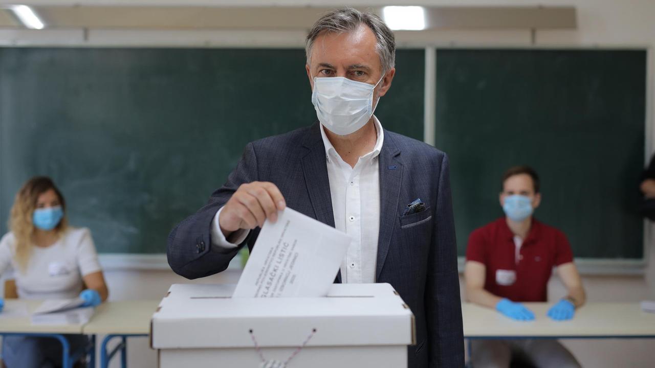 Miroslav Skoro, kroatischer Musiker und nationalistischer Kandidat bei der Parlamentswahl, gibt mit Mund-Nasen-Bedeckung seine Stimme ab.