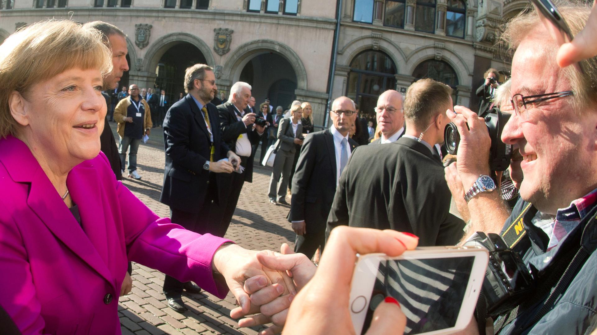 Bundeskanzlerin Angela Merkel (CDU) spricht am 03.10.2014 mit Zuschauern beim Tag der Deutschen Einheit an der Marktkirche in Hannover (Niedersachsen). Bundeskanzlerin Angela Merkel (CDU) spricht am 03.10.2014 mit Zuschauern beim Tag der Deutschen Einheit an der Marktkirche in Hannover (Niedersachsen).