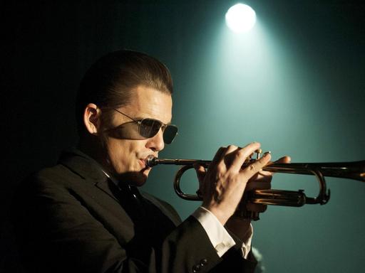 Ethan Hawke als Jazztrompeter Chet Baker, mit Sonnenbrille und schwarzem Anzug im spärlichen Licht eines einzelnen Scheinwerfers (Bild: Alamode Film / Born to be Blue)