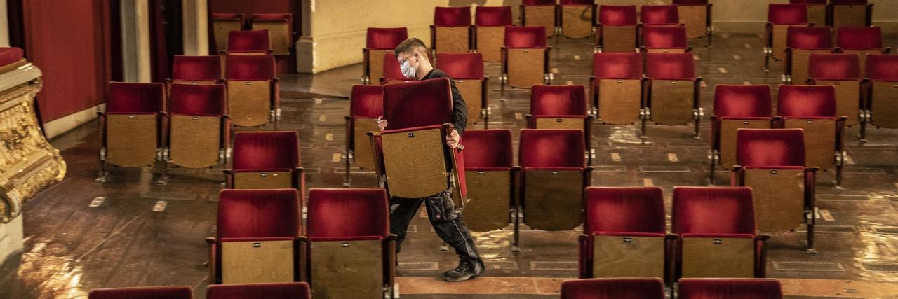 Ein Mann entfernt Stühle aus dem Zuschauerraum eines Theaters Ein Mann entfernt Stühle aus dem Zuschauerraum eines Theaters