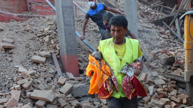 Ein Helfer trägt nach dem Erdbeben in Nepal Heiligenfiguren aus den Trümmern eines Tempels.