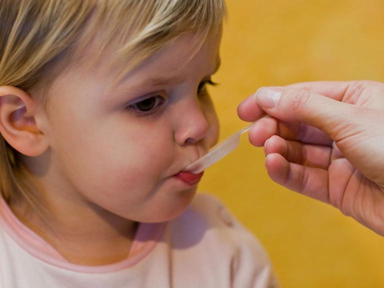 Eine Mutter gibt ihrem Kind ein homöopathisches Mittel.