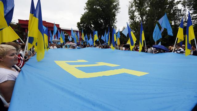 Menschen halten eine Flagge der Krimtataren in Händen. Sie erinnern in Kiew an den 70. Jahrestag der Krim-tatarischen Deportation. (Archivbild 2014)