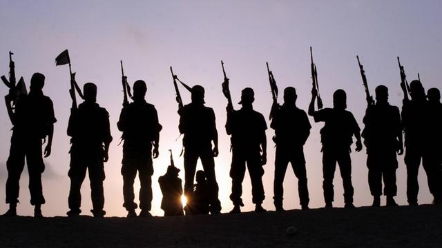 Silhouetten einer Gruppe von mutmaßlichen IS-Kämpfern in einer Reihe aufgestellt.