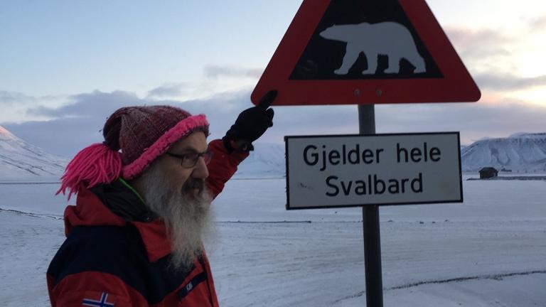 Polarforscher Kim Holmen vor einem Eisbär-Warnschild auf Spitzbergen Polarforscher Kim Holmen vor einem Eisbär-Warnschild auf Spitzbergen