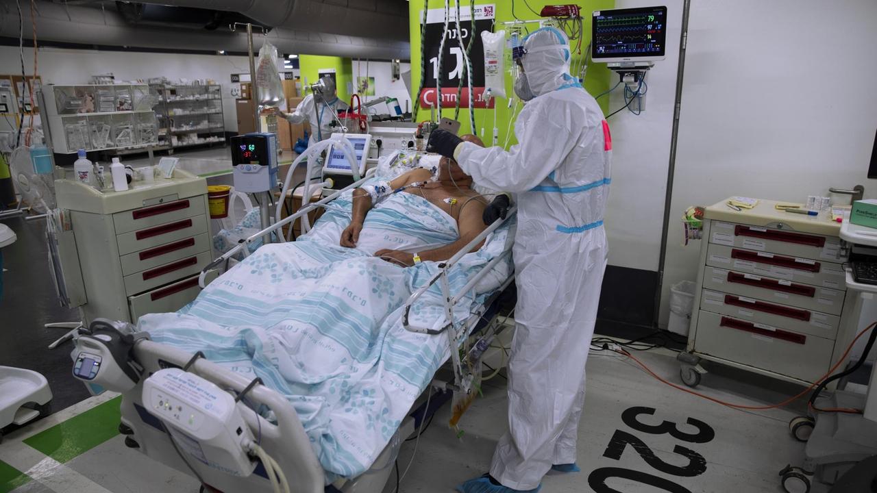 Patient in einer COVID-19 Station in einem Parkhaus in Haifa. Ein Krankenpfleger hält ihm eine Telefon vor die Augen, damit er Kontakt zu seinen Angehörigen haben kann. Das Medizinische Personal vom Rambam Krankenhaus kann innerhalb von 72 Stunden eine Intensivstation im Parkhaus aufbauen, seit September wird es genutzt. Aufnahme vom 15.12.2020. Patient in einer COVID-19 Station in einem Parkhaus in Haifa. Ein Krankenpfleger hält ihm eine Telefon vor die Augen, damit er Kontakt zu seinen Angehörigen haben kann. Das Medizinische Personal vom Rambam Krankenhaus kann innerhalb von 72 Stunden eine Intensivstation im Parkhaus aufbauen, seit September wird es genutzt. Aufnahme vom 15.12.2020.
