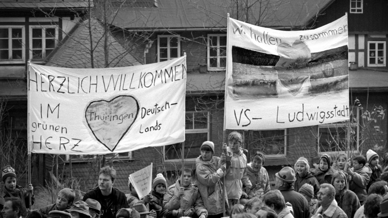 Schüler halten Begrüßungstransparente für die Bürger der DDR in die Höhe.