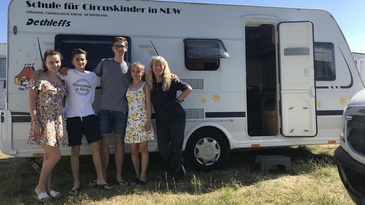 Die Schüler Jenna, Jamie, Toni und Angeli stehen mit der Lehrerin Bärbel Fritz vor Schulwagen in Düsseldorf. Die Schüler Jenna, Jamie, Toni und Angeli stehen mit der Lehrerin Bärbel Fritz vor Schulwagen in Düsseldorf.