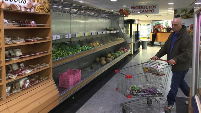 Ein Mann fährt mit einem Einkaufswagen durch einen Supermarkt in Caracas