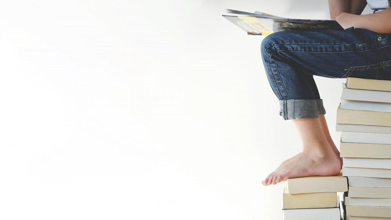 Eine Frau sitzt auf einem Bücherstapel. Eine Frau sitzt auf einem Bücherstapel.