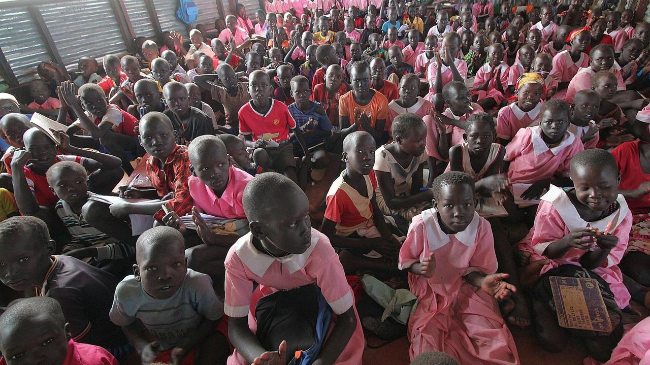 Ein Klassenraum voller Grundschulkinder, ohne Tische und Stühle