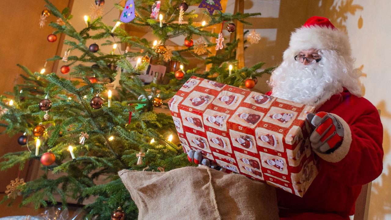 Der Weihnachtsmann sitzt zur Bescherung in einem Haus neben einem geschmückten Weihnachtsbaum Der Weihnachtsmann sitzt zur Bescherung in einem Haus neben einem geschmückten Weihnachtsbaum