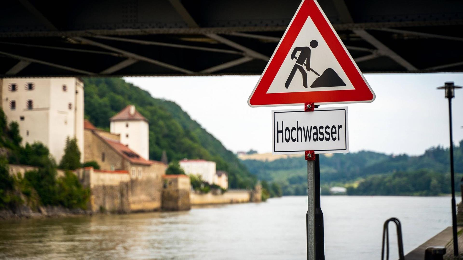 Hochwasser in Passau: Fluss mit Straßenschild, Brücke und Häuser.