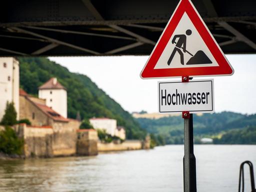 Hochwasser in Passau: Fluss mit Straßenschild, Brücke und Häuser.