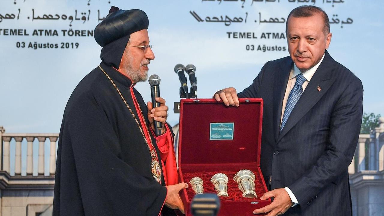 Der syrisch-orthodoxe Patriarch Yusuf Cetin (links) überreicht Präsident Erdogan bei der Grundsteinlegung für die erste christliche Kirche seit 1923 ein Geschenk. Der syrisch-orthodoxe Patriarch Yusuf Cetin (links) überreicht Präsident Erdogan bei der Grundsteinlegung für die erste christliche Kirche seit 1923 ein Geschenk.