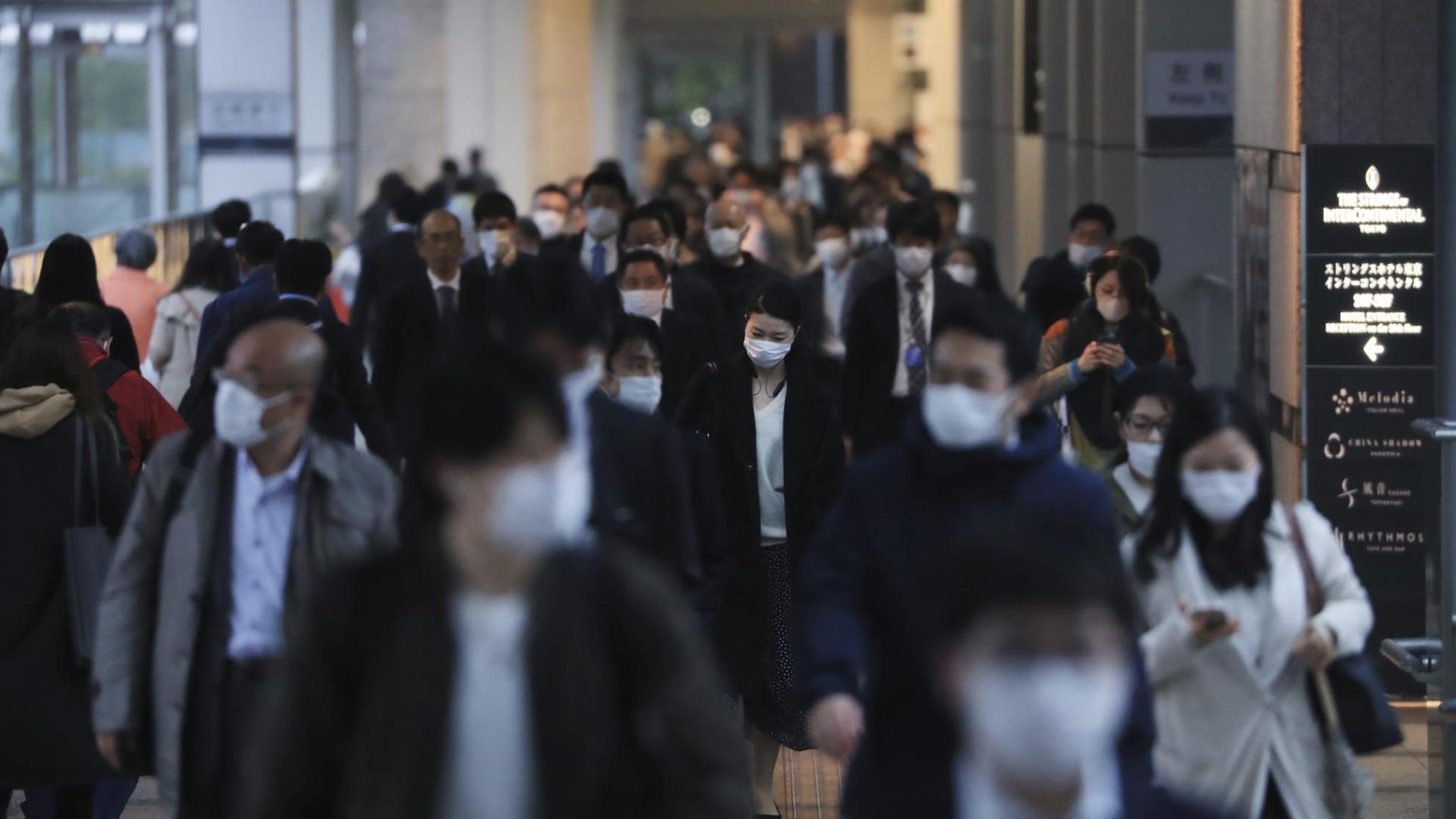 Menschen mit Masken in der Shinagwa Station in Tokio. Menschen mit Masken in der Shinagwa Station in Tokio.