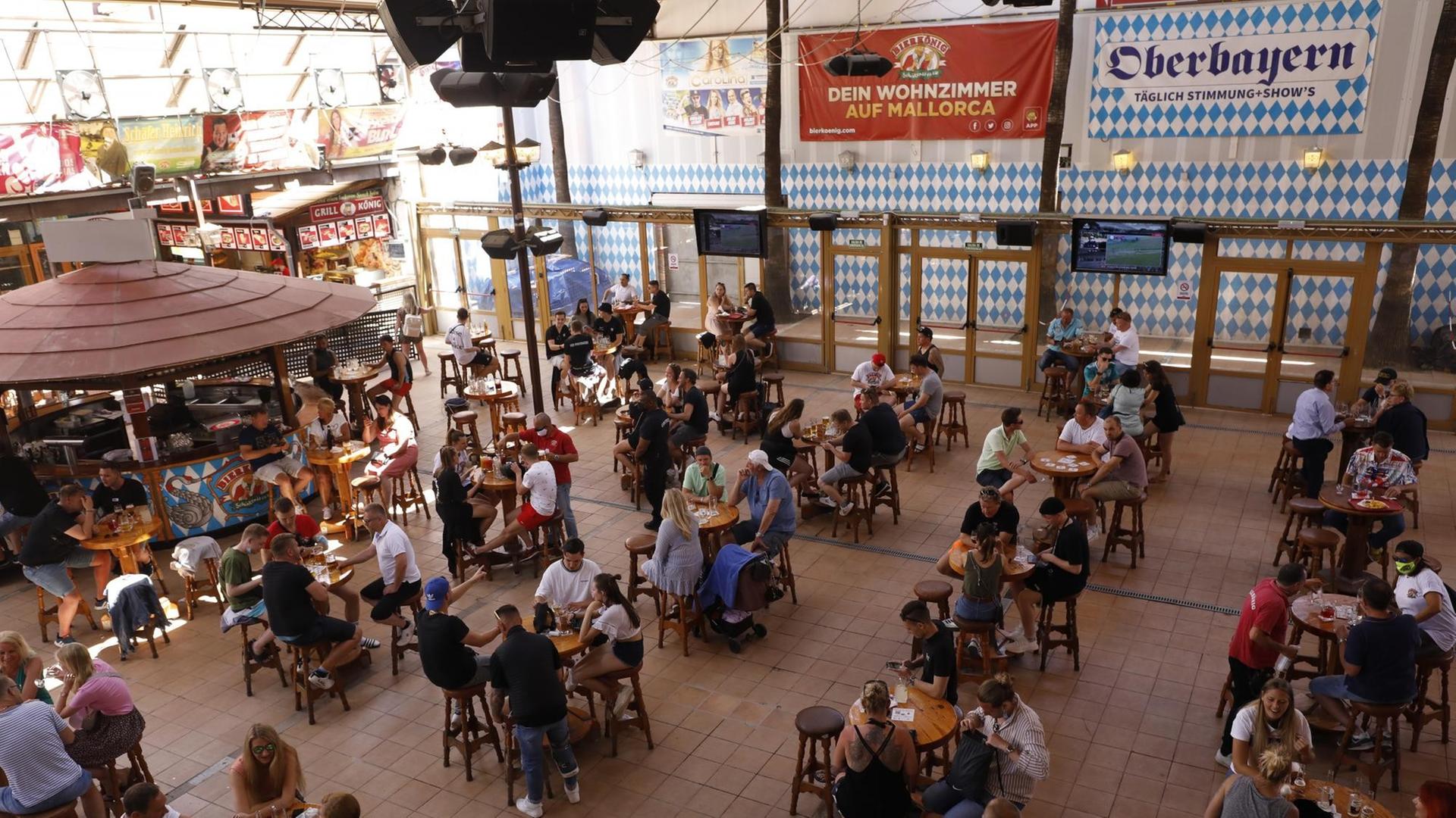 Gäste sitzen an Tischen im Lokal "Bierkönig" auf Mallorca. Das Lokal hat nach Monaten der Schließung wieder geöffnet. Allerdings gelten noch diverse Corona-Auflagen für die Gäste.