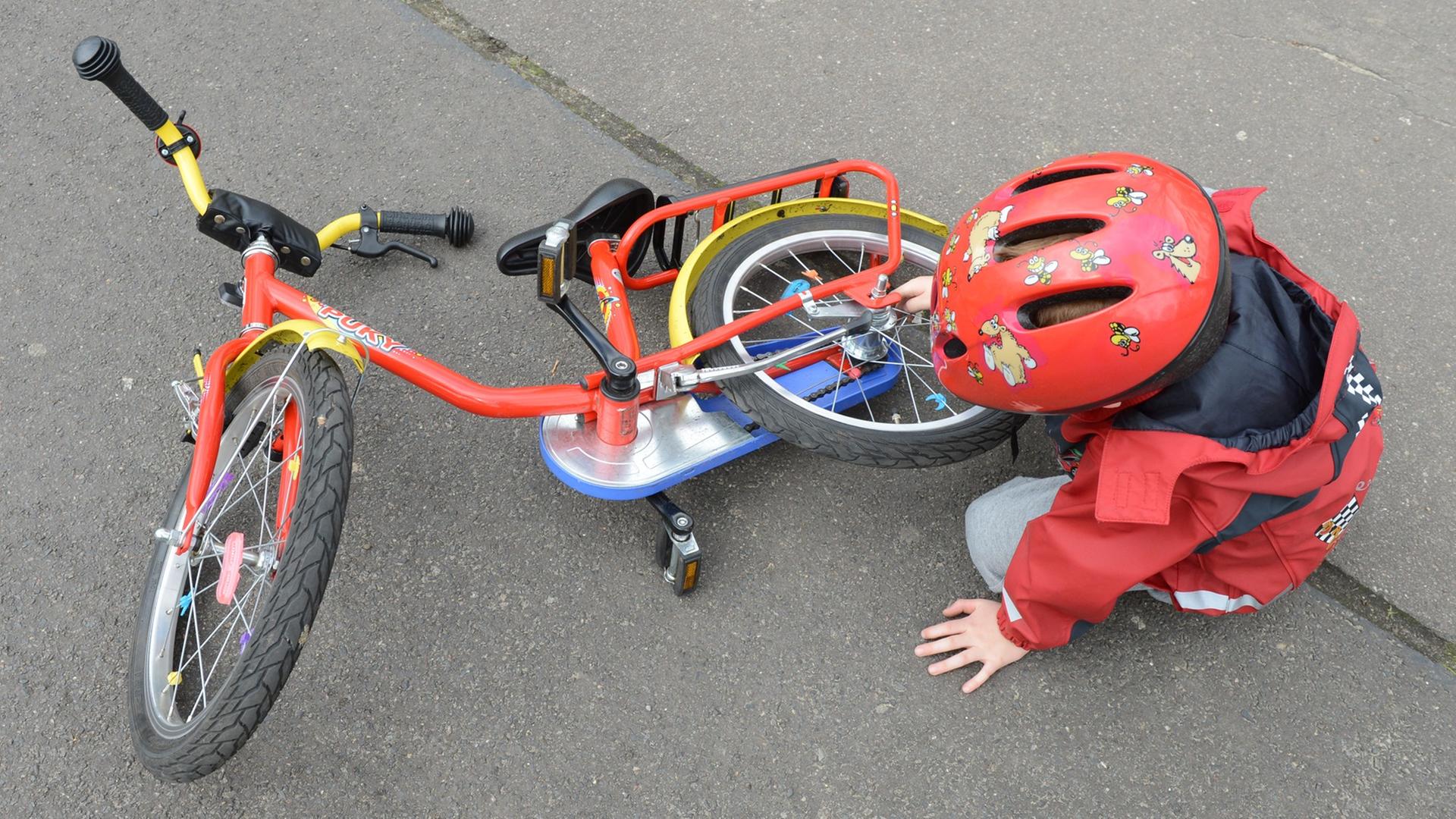 Ein Kind sitzt neben seinem Fahrrad auf der Straße. Ein Kind sitzt neben seinem Fahrrad auf der Straße.