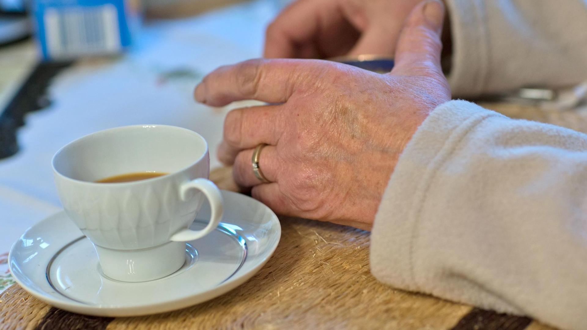 In der Küche einer Senioren-WG. Eine Bewohnerin sitzt vor einer Kaffeetasse. In der Küche einer Senioren-WG. Eine Bewohnerin sitzt vor einer Kaffeetasse.