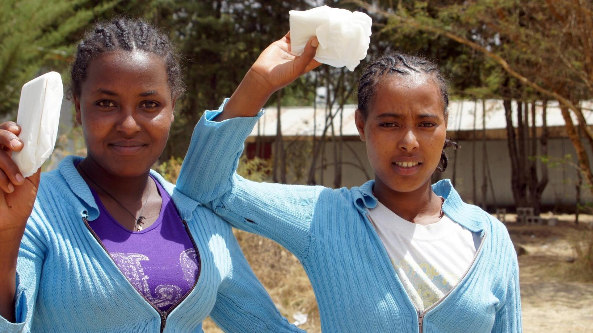 Schülerinnen in Äthiopien halten nach der Sexualaufklärung Binden hoch