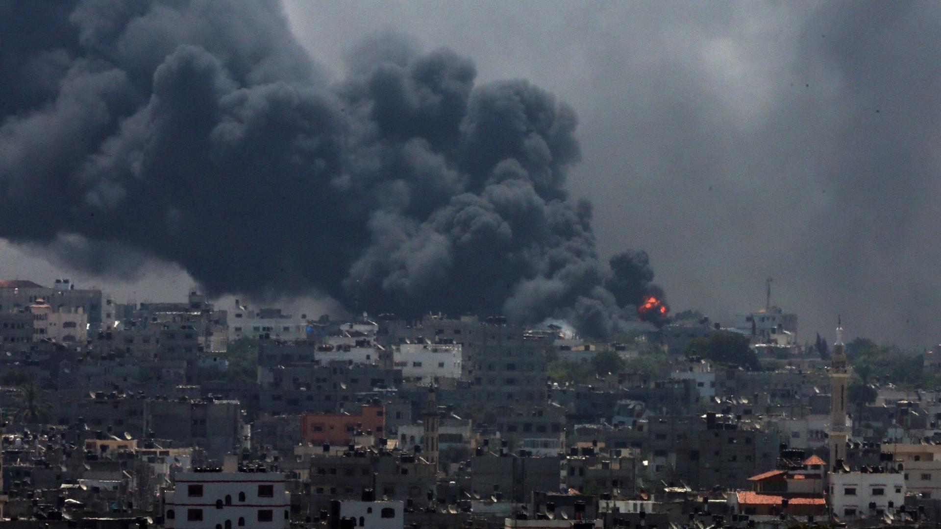 Panorama-Ansicht von Al Shejaeiya: Ein Haus auf einem Hügel brennt, von dort aus steigt eine dichte Wolke mit schwarzem Rauch über die Stadt auf. Panorama-Ansicht von Al Shejaeiya: Ein Haus auf einem Hügel brennt, von dort aus steigt eine dichte Wolke mit schwarzem Rauch über die Stadt auf.