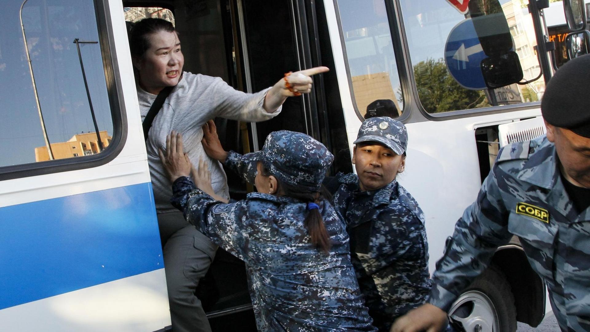 Eine Frau wird während einer Demonstration gegen die kasachische Regierung am 6. Juli in der Hauptstadt Nur-Sultan verhaftet. Polizeibeamte schieben eine Frau in einen Bus. Eine Frau wird während einer Demonstration gegen die kasachische Regierung am 6. Juli in der Hauptstadt Nur-Sultan verhaftet. Polizeibeamte schieben eine Frau in einen Bus.