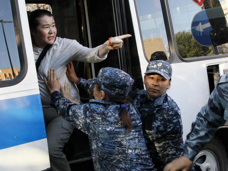 Eine Frau wird während einer Demonstration gegen die kasachische Regierung am 6. Juli in der Hauptstadt Nur-Sultan verhaftet. Polizeibeamte schieben eine Frau in einen Bus.