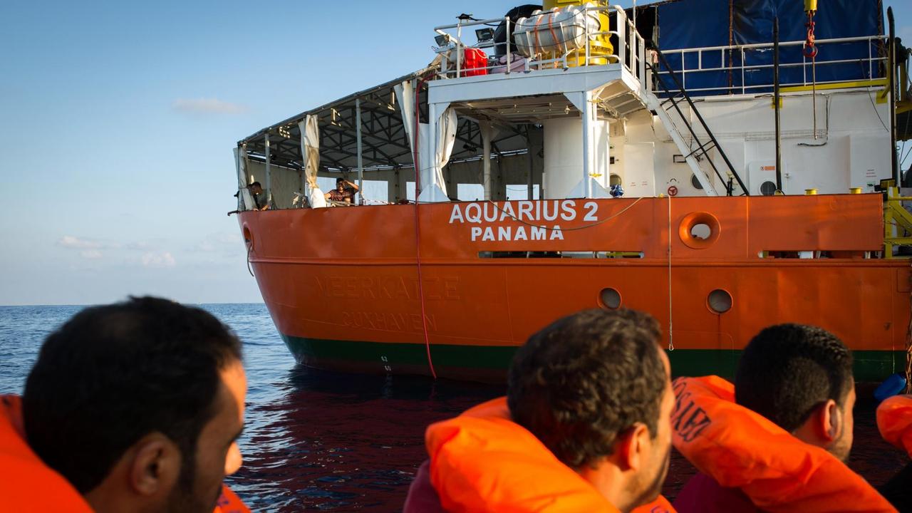 Flüchtlinge blicken von einem Boot vor Malta aus zum Seenotrettungsschiff Aquarius 2 der Hilfsorganisation SOS Méditerranée.