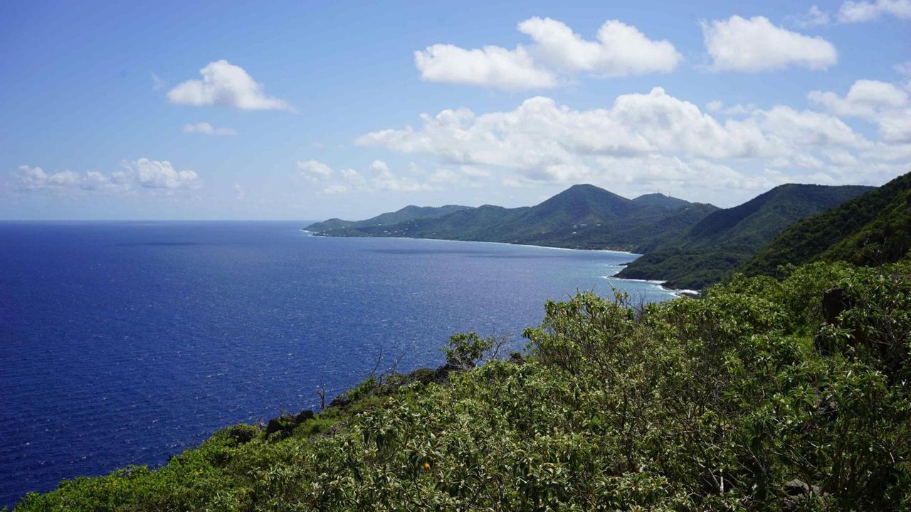 Man sieht von oben das blaue Meer und etwas Wald auf der Insel Man sieht von oben das blaue Meer und etwas Wald auf der Insel