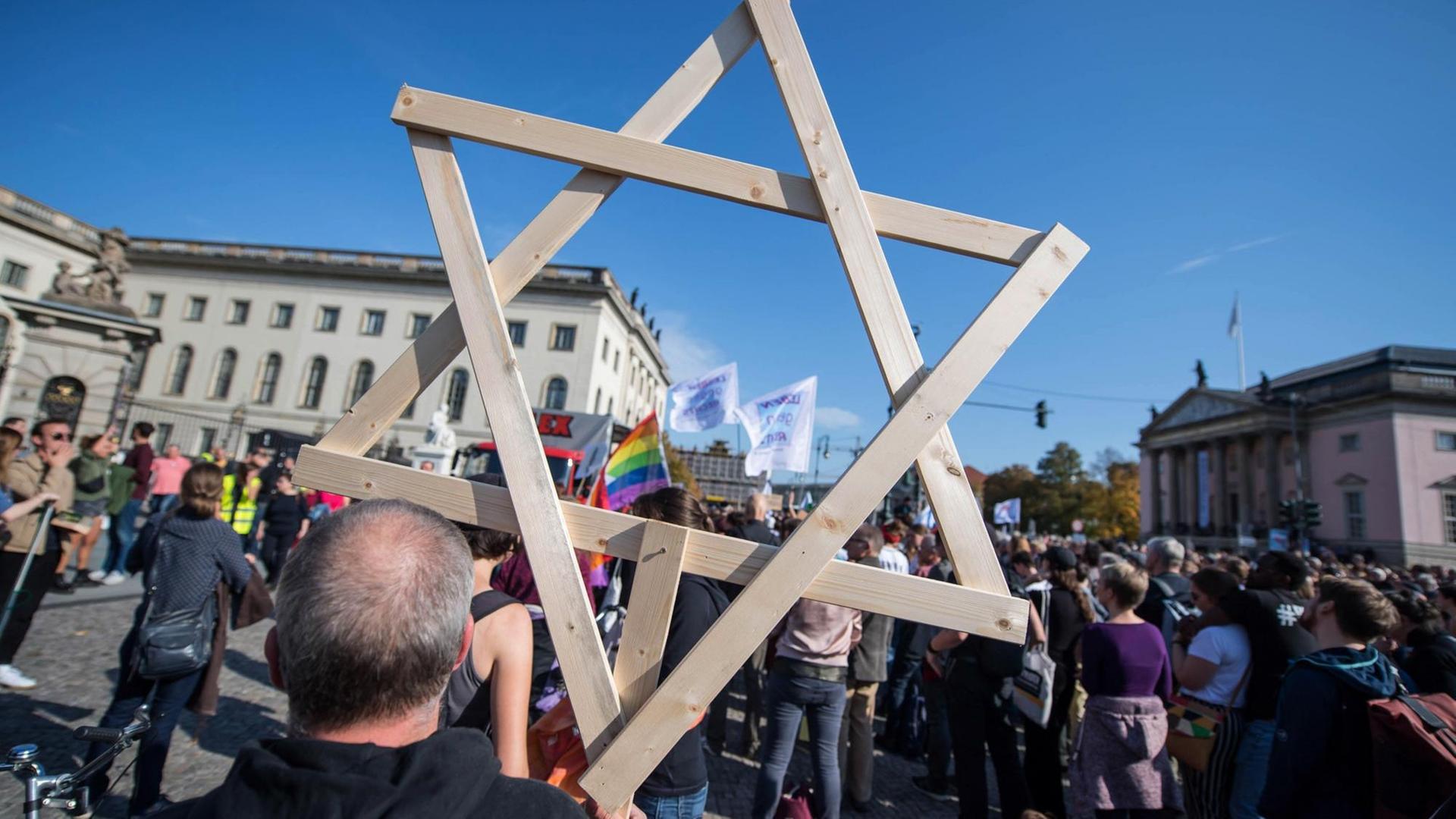 Ein Mann auf der Berliner Unteilbar-Demonstration trägt einen riesigen hölzernen Davidstern durch die Menge. Ein Mann auf der Berliner Unteilbar-Demonstration trägt einen riesigen hölzernen Davidstern durch die Menge.