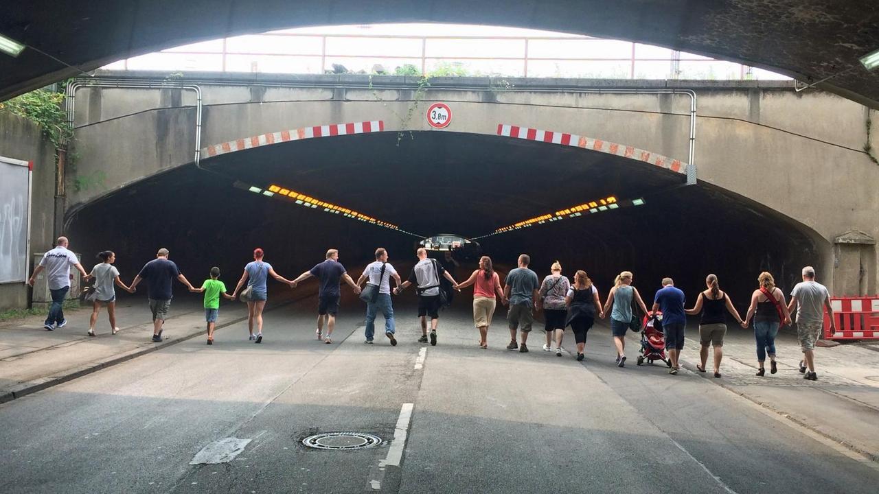 Menschen gehen Hand in d Hand auf einen Tunnel zu.