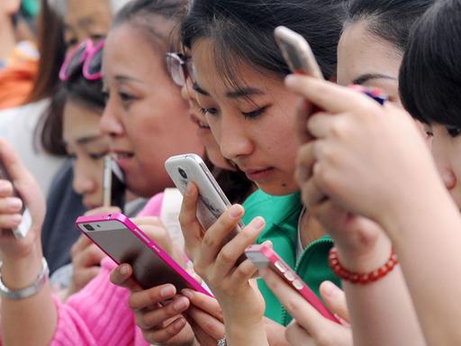 Junge Chinesinnen benutzen am 24.4.2015 ihre Smartphones für ein Gewinnspiel in einem Einkaufszentrum in Taiyuan im Norden Chinas.