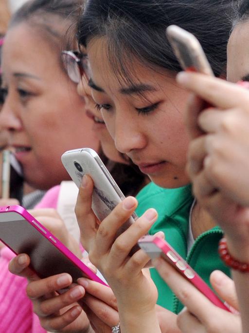 Junge Chinesinnen benutzen am 24.4.2015 ihre Smartphones für ein Gewinnspiel in einem Einkaufszentrum in Taiyuan im Norden Chinas.