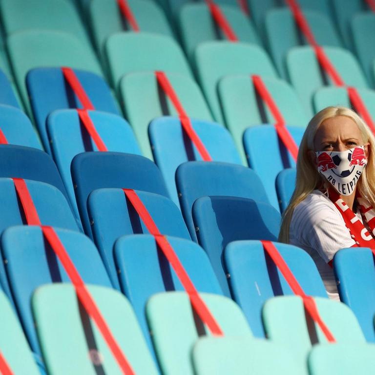Eine Zuschauerin mit Maske vor ansonsten leeren Rängen in der Red Bull Arena in Leipzig. 

