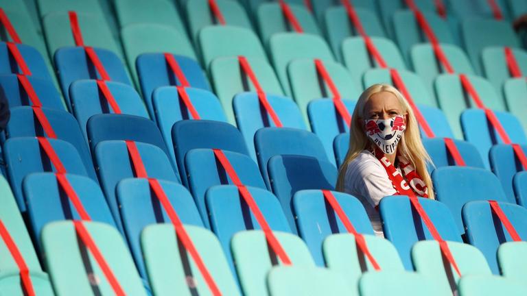 Eine Zuschauerin mit Maske vor ansonsten leeren Rängen in der Red Bull Arena in Leipzig. 


