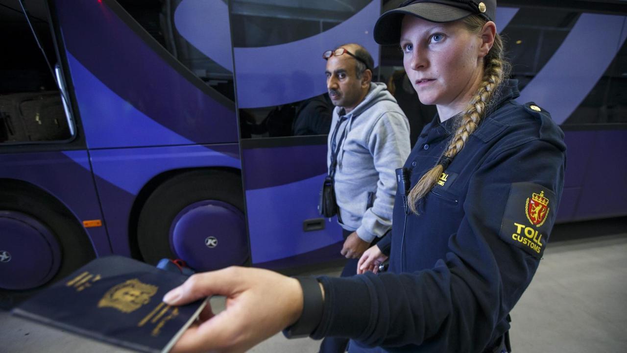 Eine norwegische Polizistin kontrolliert den Pass eines Flüchtlings. Eine norwegische Polizistin kontrolliert den Pass eines Flüchtlings.