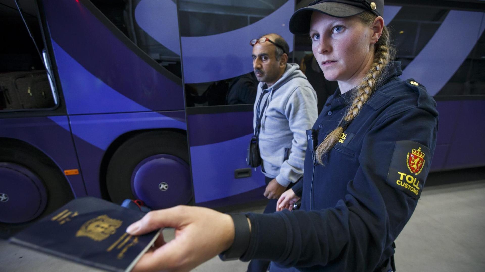 Eine norwegische Polizistin kontrolliert den Pass eines Flüchtlings. Eine norwegische Polizistin kontrolliert den Pass eines Flüchtlings.