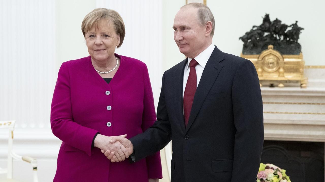 Bundeskanzlerin Merkel und der russische Präsident Putin geben sich die Hand und schauen zu den Fotografen. Bundeskanzlerin Merkel und der russische Präsident Putin geben sich die Hand und schauen zu den Fotografen.