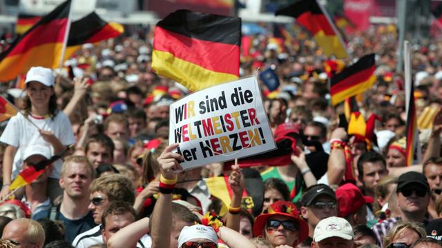Menschen auf der Fanmeile in Berlin halten am 9. Juli 2006 ein Schild hoch mit der Aufschrift "Wir sind die Weltmeister der Herzen"