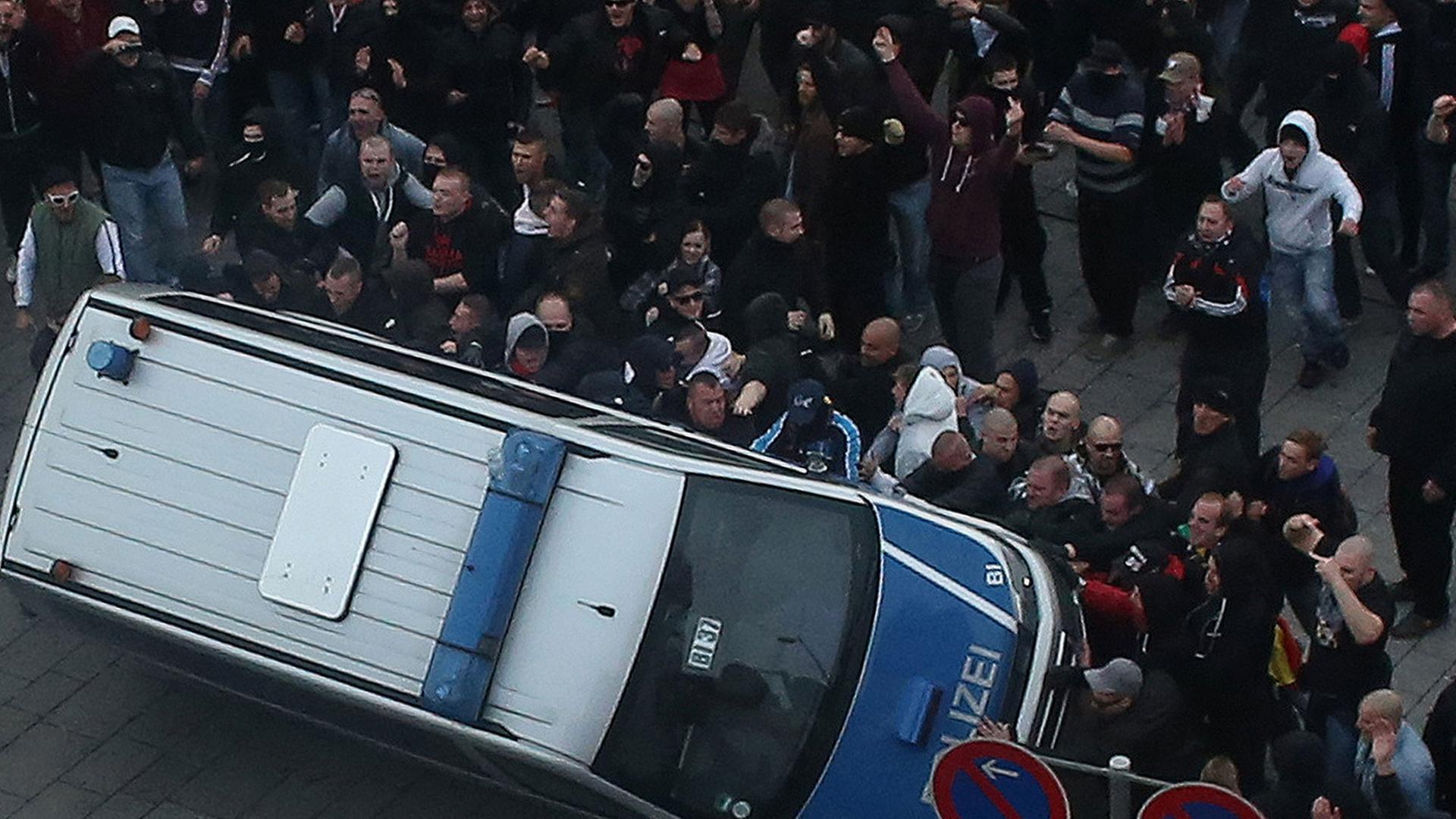 Bei einer Demonstration der Gruppe "Hooligans gegen Salafismus" in Köln wird ein Polizeiauto umgeworfen. Bei einer Demonstration der Gruppe "Hooligans gegen Salafismus" in Köln wird ein Polizeiauto umgeworfen.