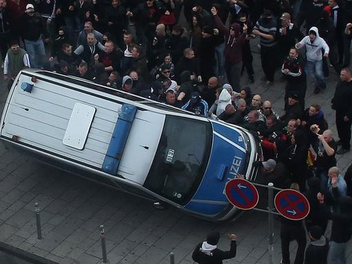 Bei einer Demonstration der Gruppe "Hooligans gegen Salafismus" in Köln wird ein Polizeiauto umgeworfen.