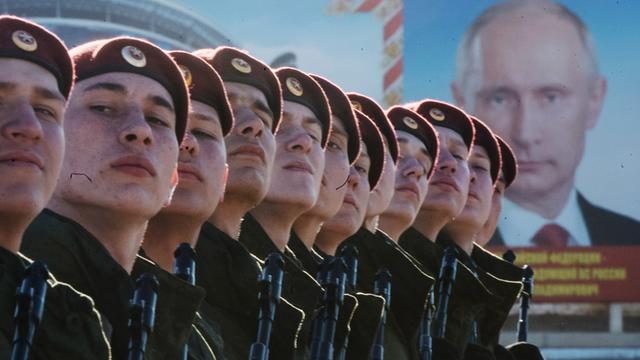 Russische Truppen vor einem Plakat des russischen Präsidenten Wladimir Putin