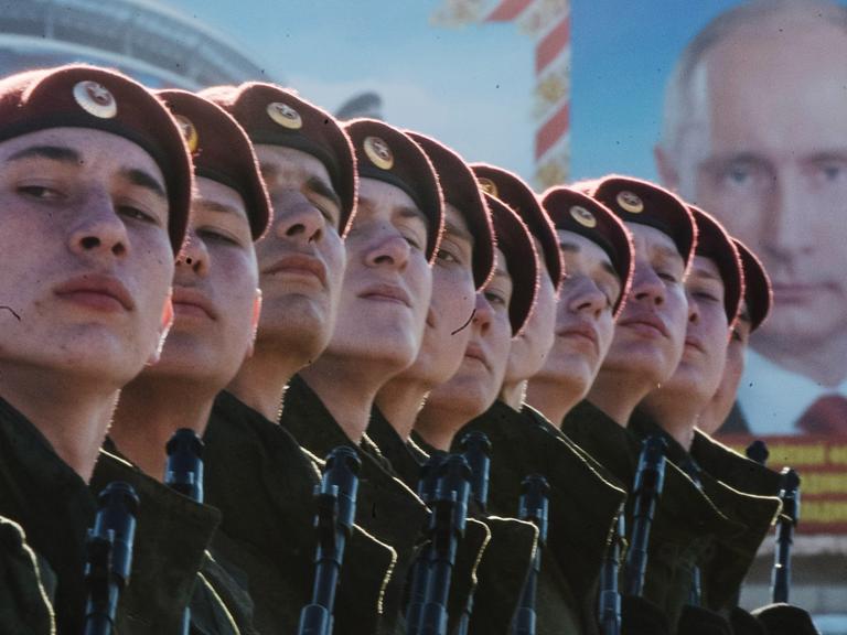 Russische Truppen vor einem Plakat des russischen Präsidenten Wladimir Putin