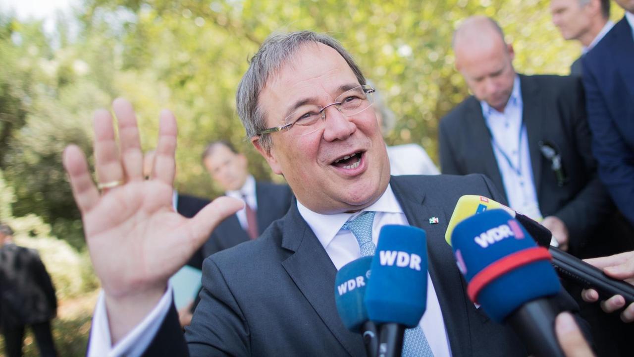 Armin Laschet (CDU), Ministerpräsident von Nordrhein-Westfalen, steht am 05.09.2018 vor mehreren WDR-Mikrofonen und winkt in die Kamera Armin Laschet (CDU), Ministerpräsident von Nordrhein-Westfalen, steht am 05.09.2018 vor mehreren WDR-Mikrofonen und winkt in die Kamera